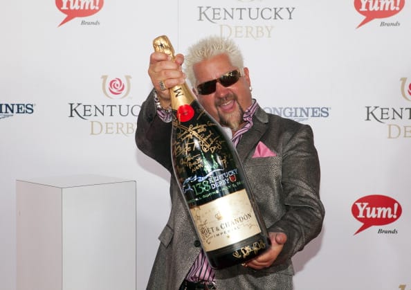 Guy Fieri signs a limited edition 6 Liter Moet & Chandon Imperial bottle for the brand's philanthropic initiative "Sign for the Roses" on the red carpet at the 138th Kentucky Derby on May 5, 2012 in Louisville, Kentucky.  (Photo by Joey Foley/Getty Images for Moet)