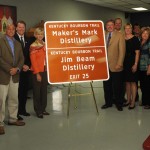 Kentucky Bourbon Trail sign unveiling Representatives from the Kentucky Bourbon industry join First Lady Jane Beshear and elected officials in unveiling the first of 17 new Kentucky Bourbon Trail interstate signs. (Left to right): Rep. Linda Belcher; Geri Grigsby (Kentucky Transportation Cabinet); Sen. Jimmy Higdon; Jeff Conder (Beam Global Spirits & Wine); Versailles Mayor Fred Siegelman; KDA President Eric Gregory; First Lady Jane Beshear; Kevin Smith (Maker’s Mark); Greg Davis (Maker’s Mark); Marnie Walters (Woodford Reserve); Larry Kass (Heaven Hill); Secretary Marcheta Sparrow (Tourism, Arts & Heritage Cabinet); Franklin County Judge-Executive Ted Collins; Jim Rutledge (Four Roses); Jimmy Russell (Wild Turkey).